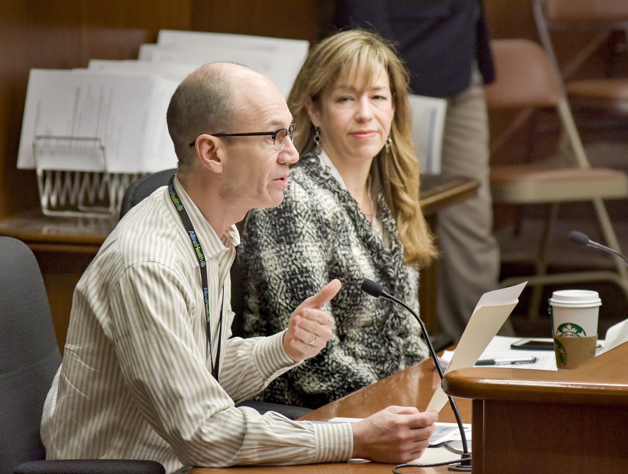 Dr. Paul Goering, vice president at Allina Mental Health and Addiction services, testifies before the House Health and Human Services Reform Committee Feb. 9 in support of a bill sponsored by Rep. Roz Peterson, right, that would establish a mental health innovation grant program.  Photo by Andrew VonBank